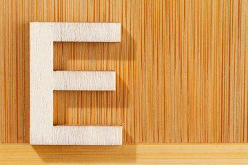 Letter E of wood-made alphabet, top view and space for text