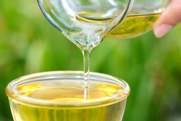 Pouring olive oil in the a glass bowl at stone kitchen and inside green garden view. Prepare for cooking concept. Healthcare and Beauty Concept.