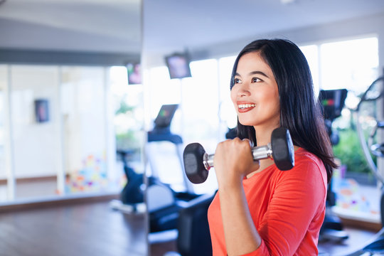 Pretty Indonesian Woman Lifting Weights In Gym