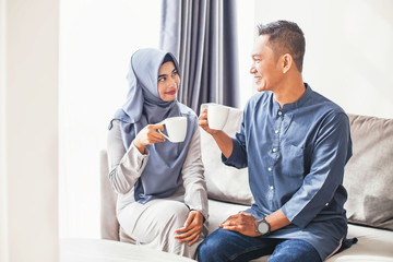 Beautiful indonesian muslim couple drinking coffee at home