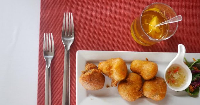 traveling shot of cod fritters, accras de morue, french Caribbean style holiday food on white rectangle plate with rum and white and red table