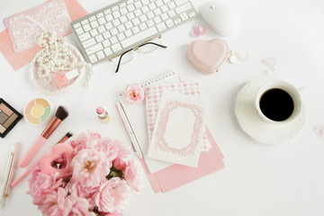 Flat lay, top view office table desk . Feminine desk workspace with laptop, bouquet of pink roses, glasses,cup of coffee, makeup cosmetics, card mock up on white background. Holiday 