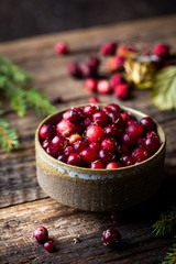 Cranberries in a handmade bowl on rustic wooden background.