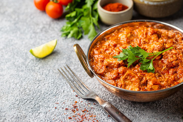 Chicken meat with tikka masala sauce, spicy curry food in iron copper pot with seasonings
