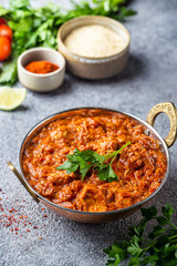 Chicken meat with tikka masala sauce, spicy curry food in iron copper pot with seasonings