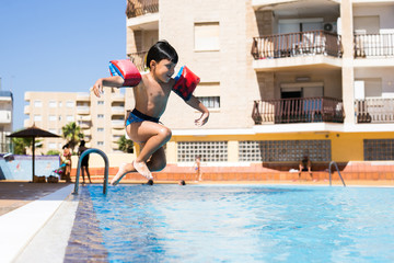 Child jumping into a swimming pool
