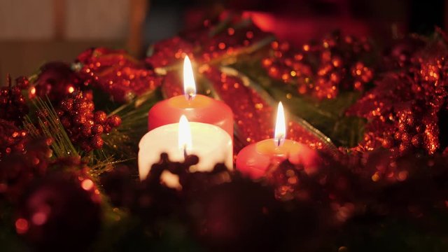 Closeup 4k footage of three red and white candles burning in advent Christmas wreath at night. Perfect background or backdrop for Christmas or New Year