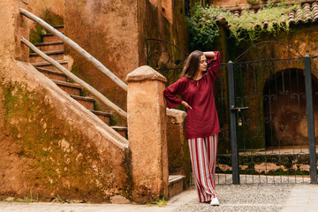 Superb young girl with long dark hair in a burgundy blouse and striped trousers turned on the...