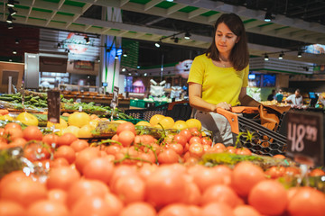 Obraz premium woman choosing vegetables from store shelf grocery shopping