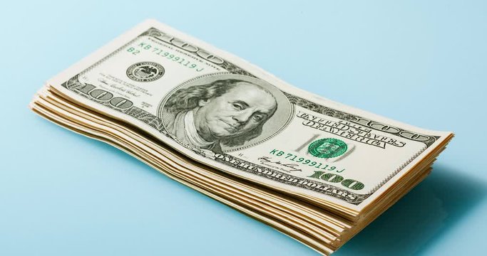 Growing up and down bundle of 100 dollars bills on the blue background, timelapse