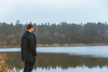 man in autumn outfit looking at misty lake