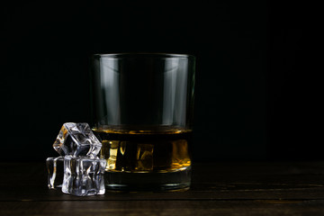 glass of whiskey and ice on black background