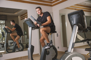 An athlete is engaged in the gym, a Young man does cardio on an exercise bike