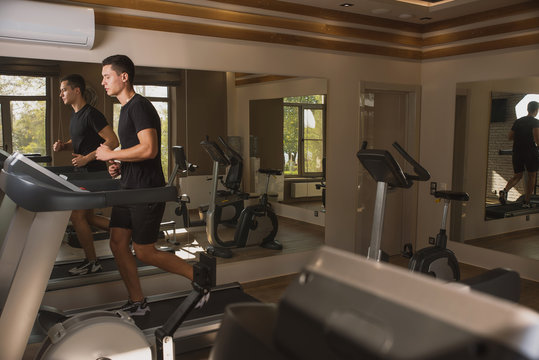 Athlete engaged in the gym, a Young man doing cardio on the treadmill - Powered by Adobe