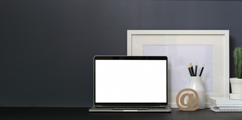 Minimal workspace with open blank screen laptop computer and mock up frame