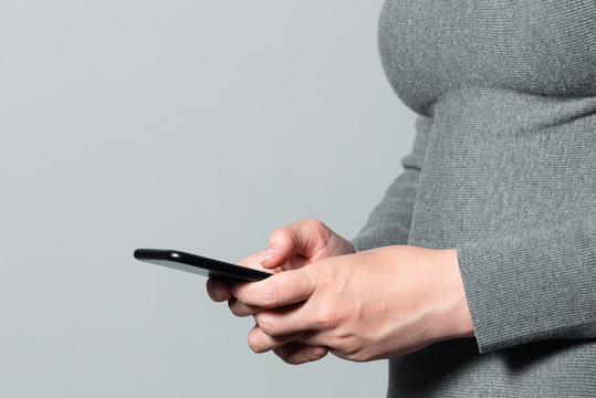 Mobile phone in female hand isolated on gray background.