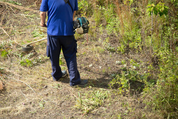 草刈機で草を刈る作業員の男性