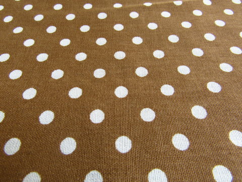 white polka dot design fabric background on light brown background seen in perspective