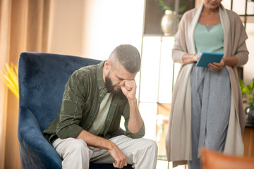 Bearded man having headache while listening to psychoanalyst