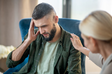 Man having headache while sharing concerns with psychoanalyst