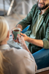 Man smiling while taking cup of tea from psychologist