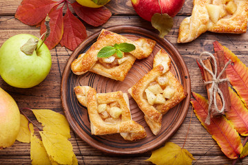 Fototapeta premium Delicious puff pastries with apples, plums and cinnamon. Sweet autumn dessert.