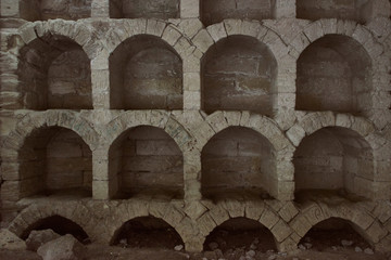 Ancient empty wine warehouse inside a cave. Old stone arches used to store bottles of wine.