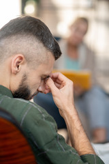 Man having headache while listening to psychoanalyst
