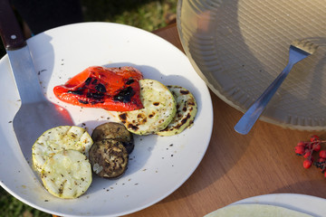 Grilled vegetables on wite plate on table, sunlight, close-up. BBQ, vegetarian concept