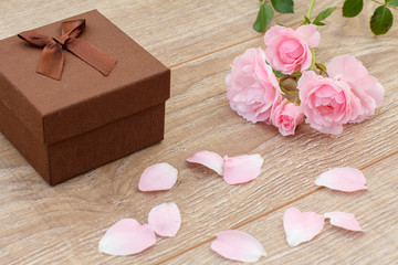Gift box with rose flowers on the wooden background.