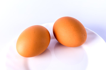 Two boiled eggs on a white plate.