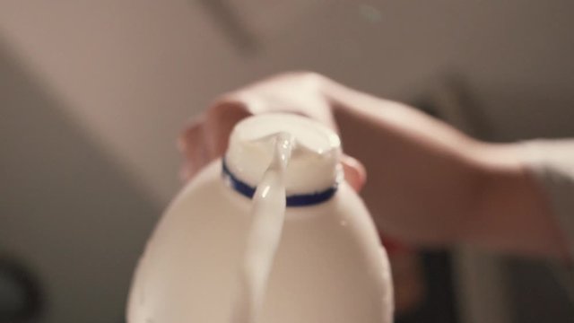 Pouring full fat milk from plastic container from above in slow motion