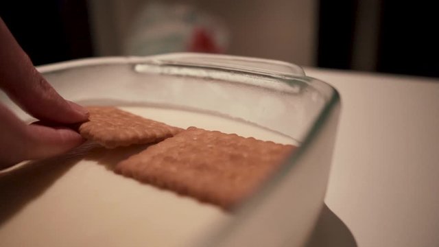 Female chef placing biscuit on whipped cream in glass dish
