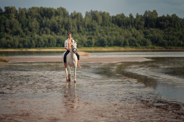 Full Length shot of man riding horse on the beach of the river