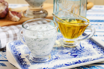 Tzatziki yogurt sauce in a small sauceboat and olive of oil.