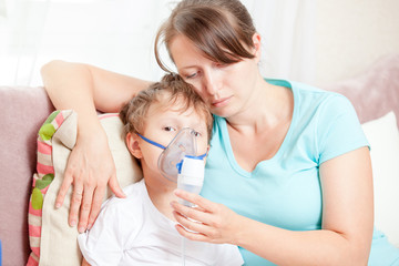 Young woman with son doing inhalation with a nebulizer at home