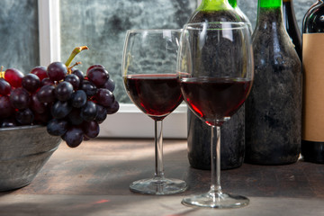 Composition with two wineglasses, grapes and bottles of red wine
