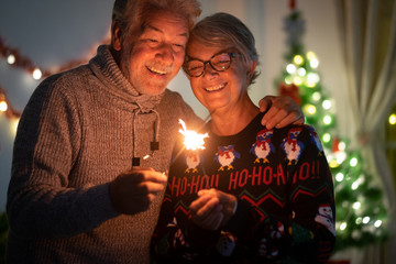 Sparkling lights and large smiles for a senior couple of grandparents celebrating the Christmas.