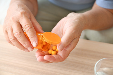 Elderly woman with pills at home, closeup