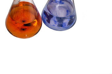 Two laboratory flasks with liquids mixed with colored chemical reagent isolated on white background. Orange and blue fluid. Close-up. Copy space