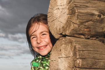 Girl playing hide and seek with dad near a wooden house in the village