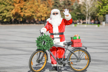 Santa Claus with bicycle and Christmas gifts outdoors