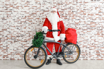 Santa Claus with Christmas gifts and bicycle near brick wall