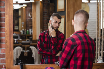 Portrait handsome man checking his haircut in mirror