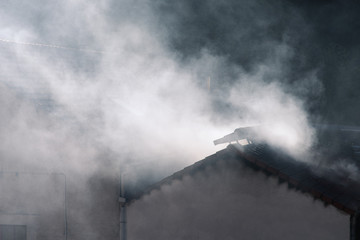 Fototapeta na wymiar De la fumée sort d'une usine. Une tonnellerie. La pollution d'une usine. Un toit amovible. Un incendie dans un bâtiment. 
