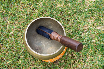 Closeup photo of Buddhist singing bowls in green grass. Meditation in nature. Balance and energy...