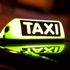 Yellow taxi sign on a taxi car roof at night