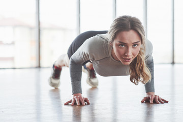 Doing push ups. Sportive young woman have fitness day in the gym at morning time