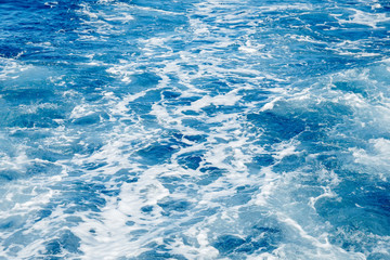Blue sea surface background with splashing waves