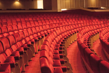 Rows of red cinema seats. View of empty theater hall. Comfort chairs in the modern theater interior